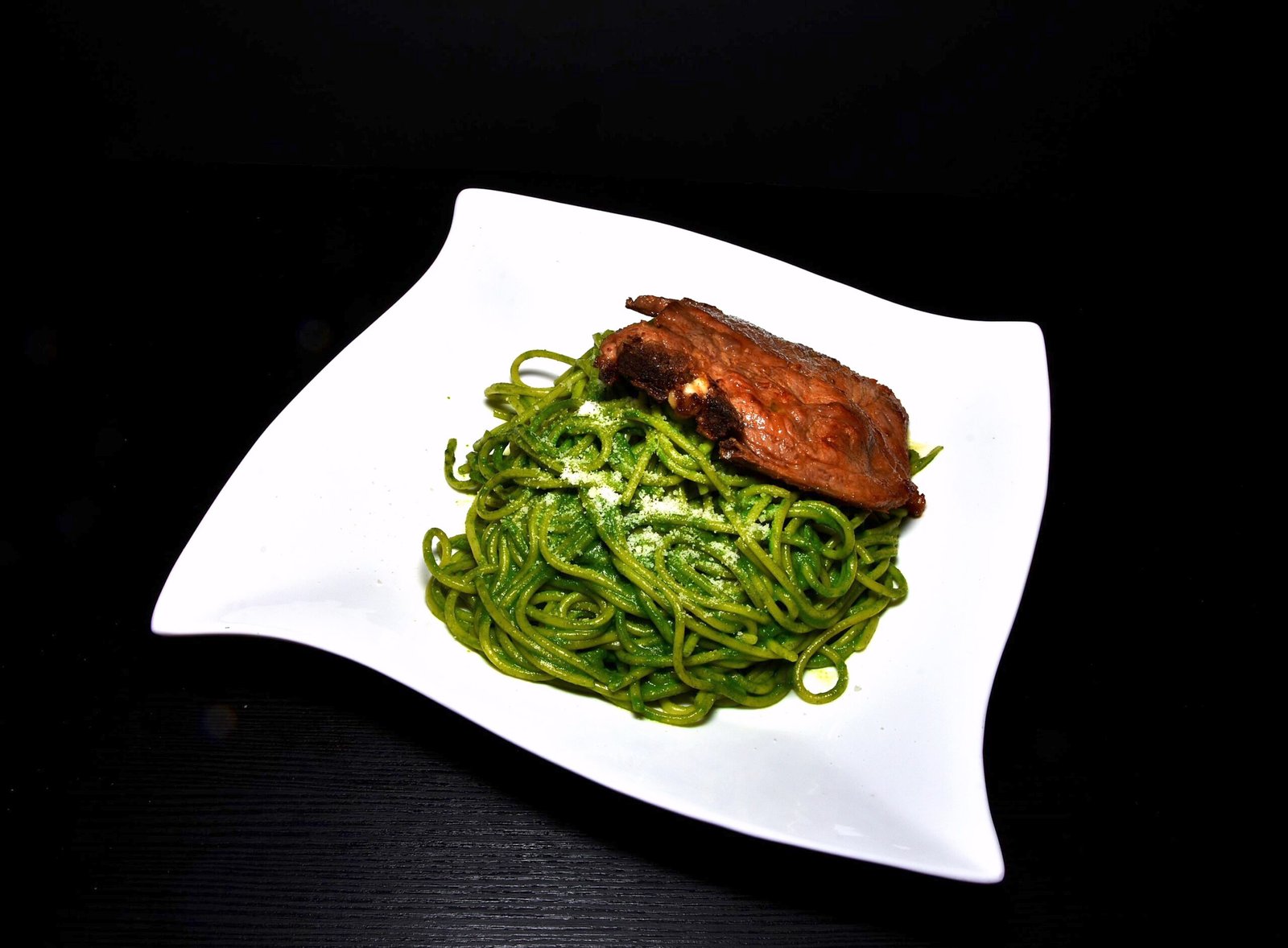 Fetuccini en salsa de albahaca acompañado de chuleta.