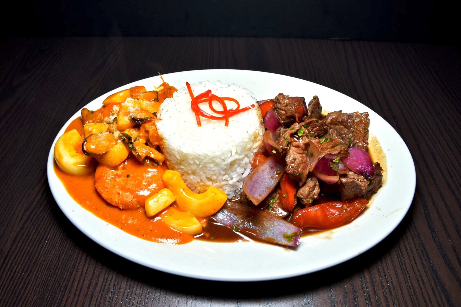 Plato Mar y Tierra, compuesto de arroz blanco largo, lomo saltado con tomate y cebolla morada y mariscos en salsa.